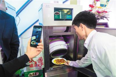 　　近日，一款商用智能自动炒菜机出现在上交会现场，现场工作人员使用该机器炒制了多款美食，吸引了观众品尝。 　　王 冈摄（人民图片）