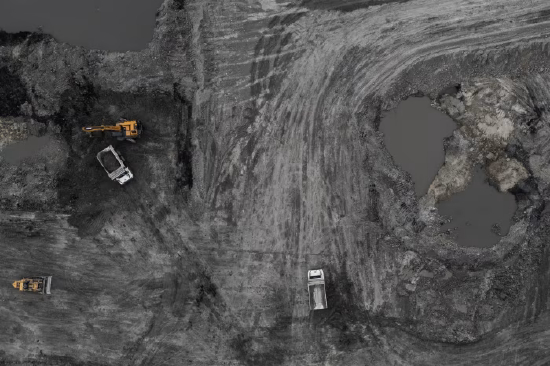 中国内蒙古一座露天煤矿，矿场内停放矿用卡车与挖掘机的航拍景象。