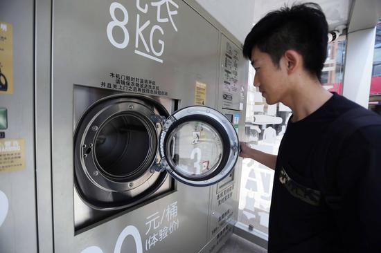 市民打开洗衣机门，查看滚筒内部。