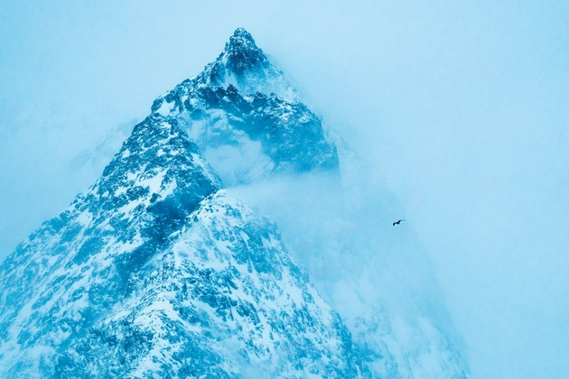 凛冽的寒风侵袭着挪威最北端峡湾的山峰，山峰上有积雪。