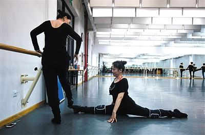 4月23日，东城第一文化馆排练厅，休息时，59岁的王洁丽在帮58岁的岳红京拉筋