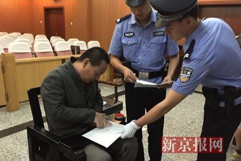 被告人田某，在法庭讯问结束后，在笔录上签字画押。新京报记者 尹亚飞 摄