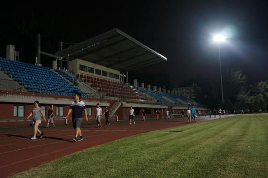 北京体育大学英东田径场，最近暑假，学校开启大灯，十分漂亮，夜跑的人们热情高涨。