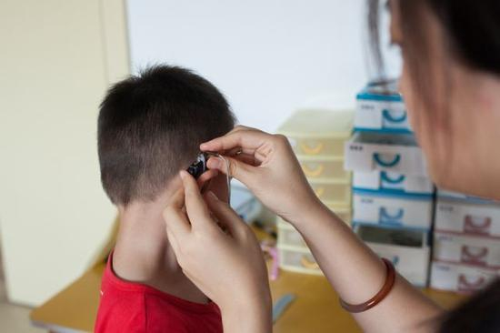 彭晓雯为午休后的小朋友佩戴助听设备（9月7日摄）。