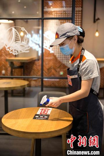 在肯德基餐厅内，工作人员对顾客使用过的餐桌进行消毒。　沙见龙 摄