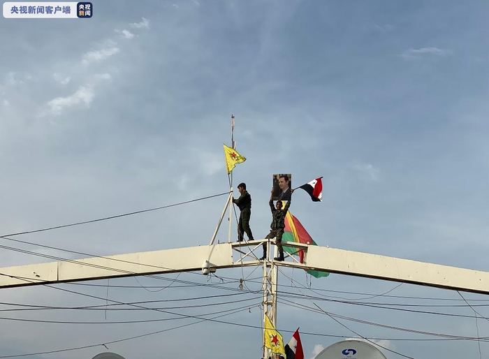 　　△叙政府军将叙利亚国旗与“人民保护部队”旗帜插到科巴尼海关大门上&nbsp; （朱雪松&nbsp;拍摄）