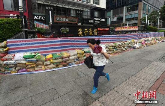 一名市民从市区五四路上一商家筑起的防御围墙前顶风前行。刘可耕 摄