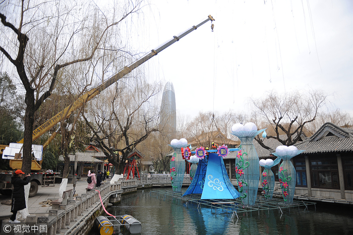 　▲2019年1月9日，济南，在天下第一泉趵突泉景区内，工作人员在园区内搭建灯架，安装各式猪年花灯。图片来自视觉中国。