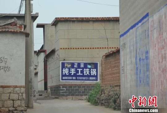 　　图为在章丘相公庄镇河庄村，“正宗纯手工铁锅”“舌尖上的章丘铁锅”等户外广告占据墙壁的显眼位置。　赵晓 摄