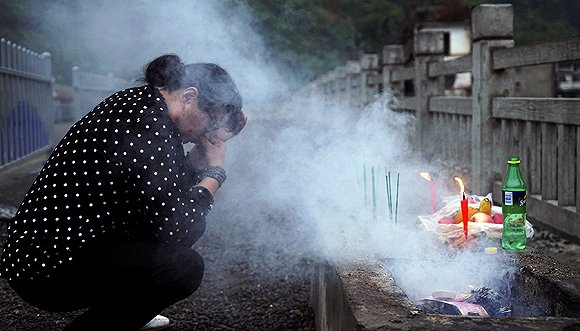 李桂花在桥上祭拜逝去的亲人。她说，“我活得很累很累，只有到你们这里来我才能说一下”。摄影：吕萌