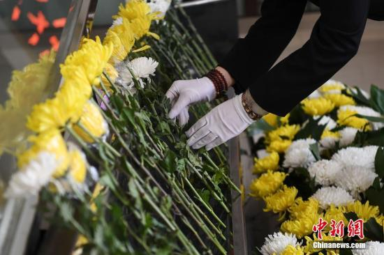 资料图：用鲜花送别死者最后一程。 武俊杰 摄