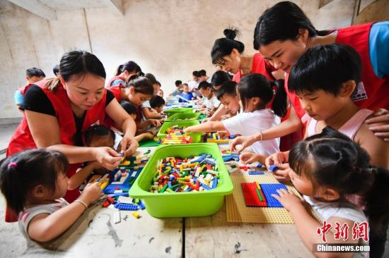 志愿者在与留守儿童一起搭积木、做游戏。 周亮 摄