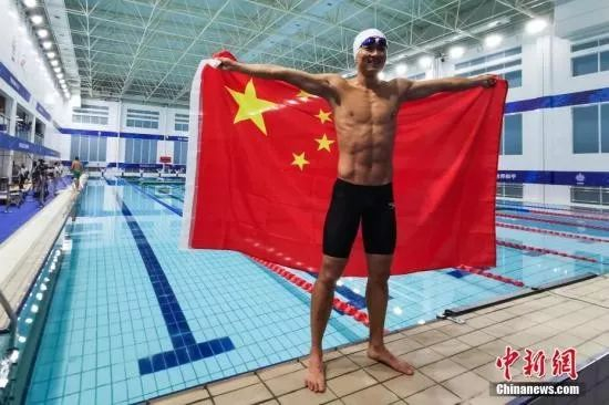  10月21日，第七届世界军人运动会军事五项障碍游泳项目中，中国选手张政以23.8秒的成绩获得第一名，并平了国际军体理事会的该项目世界纪录。图为赛后张政举起国旗庆祝。中新社记者 何蓬磊 摄