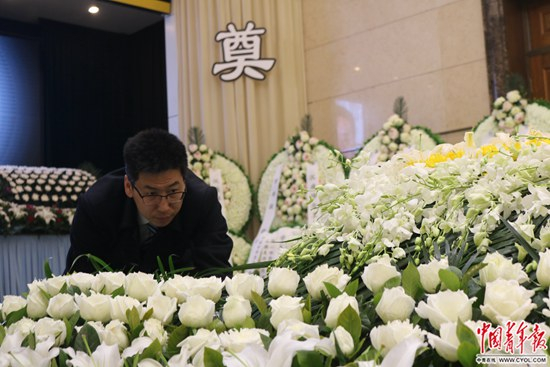 告别仪式开始前，靳中学在整理逝者遗体身旁的鲜花。