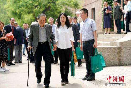 图为杨振宁、翁帆牵手离开会场。 中新社记者 杜洋 摄