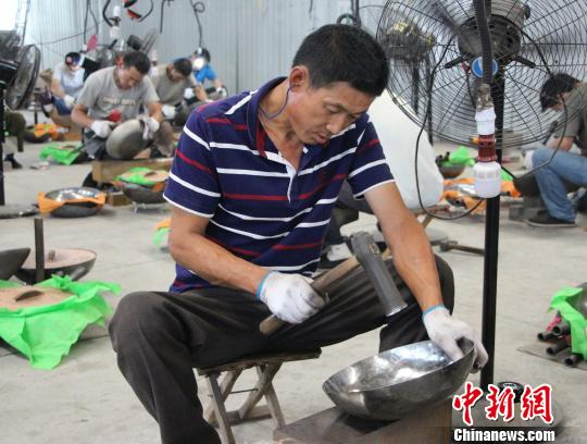 图为匠人们正手持铁锤，打制铁锅。　赵晓 摄