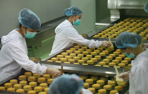 月饼工厂里女工正在给月饼刷油。