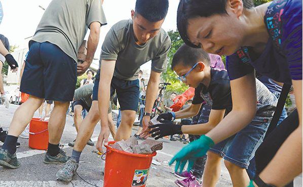 ▲驻港部队协助市民清理军营附近的路障，小朋友也“出手相助”。（《香港文汇报》）