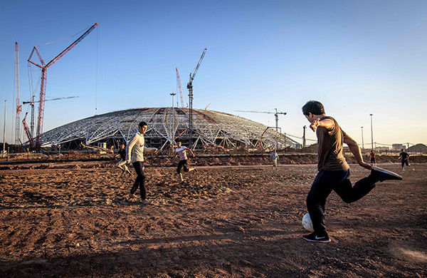 孩子们在未建成的球场工地外踢球。