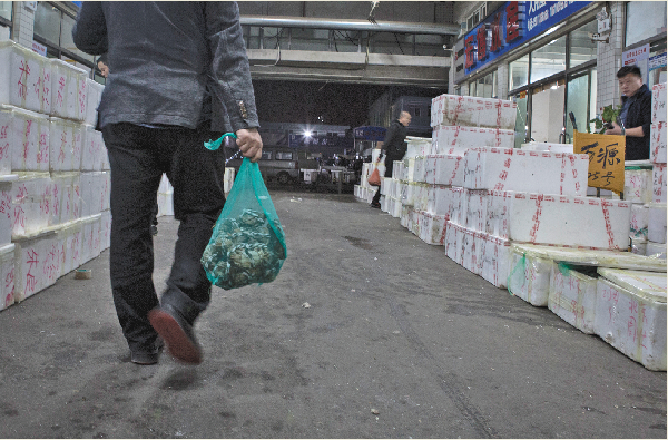 一名顾客提着刚买到的大闸蟹走出市场。新京报记者&nbsp;游天燚 摄