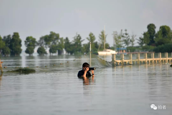  △ 2016年7月8日，湖北武汉，新京报记者陶冉在拍摄受大雨影响的城市内涝画面。摄影/和冠欣