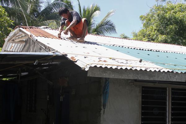 资料图：9月13日，在菲律宾坎东市，一名男子用绳子加固屋顶。新华社/法新