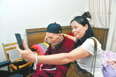 一位来客和老人自拍沾喜气。