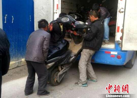 民工们奋力的将电动车搬到厢车货车上。 吴扬 摄