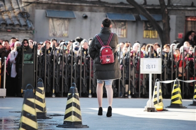 　　15日，中央戏剧学院，一位身穿裙子、脚蹬高跟鞋、背着卡通图案书包的艺考生在结束考试后走向校门，门外更是有很多等待孩子的家长。