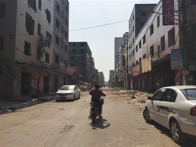 　　5月11日，郑州北郊薛岗村，一位村民骑车经过拆迁的街道。头一天，拆迁户范华培持刀杀死三人重伤一人后，被警方击毙。