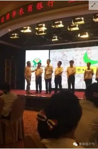 ▲手持长条状木板的中年男子手持话筒，挨个向8人问话。 视频截图