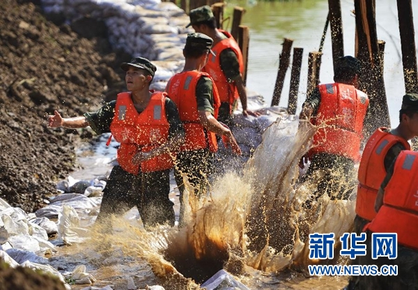 　　7月8日，武警官兵在江新洲长江堤坝上投放沙包，防止江水对堤坝造成直接冲击。受强降雨影响，江西省九江县江新洲堤坝多处出现渗水、泡泉等险情。武警江西总队一支队和九江支队的近400名官兵临危受命，驰援江新洲，采取打桩、沙包固脚等方法处理险情。新华社记者 周密 摄
