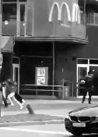 一段视频显示，右侧的黑衣男子正在对着逃跑的人们开枪射击