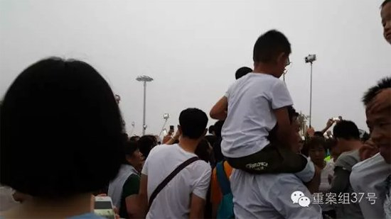 7月22日凌晨，反扒民警（白衣挎包者）在天安门观看升旗的人群中。 视频截图