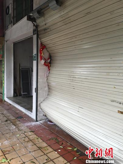 商店升降门被台风拉扯变形。 陈悦 摄