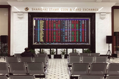 在上海邮币卡交易中心，一名投资者坐在大屏幕前盯盘。
