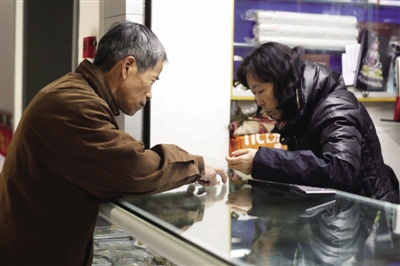 一位顾客（左）把自己收藏的纪念币转让给一名币商（右）。