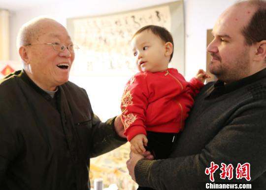 弗莱恩抱着儿子鲁克斯给长辈拜年。　胡洪涛　摄