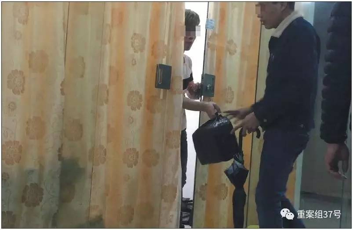 ▲3月7日傍晚，广州市越丽（国际）皮具城，拉着落地窗帘的档口开了一条缝，“跑货仔”拎着装有高仿名牌包的黑色塑料袋“串货”。新京报记者 大路 摄