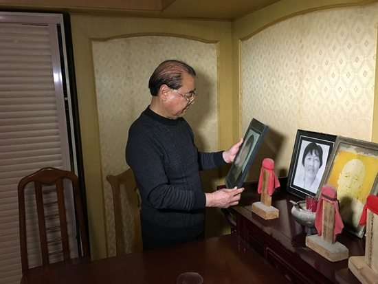 　王伯官在端详妻子遗像。