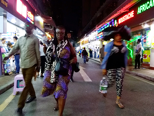 宝汉直街，形色匆匆的非洲商人，其中一个女人头顶着用来装货的黑色塑料袋。