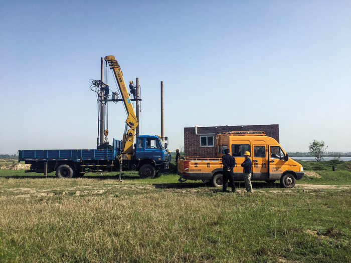 2017年4月17日上午9时许，河南省孟津县会盟镇黄河南岸。一辆电力抢险车推举着几名工人在电线杆上拆除变压器。摄影/《财经》记者 尹岳