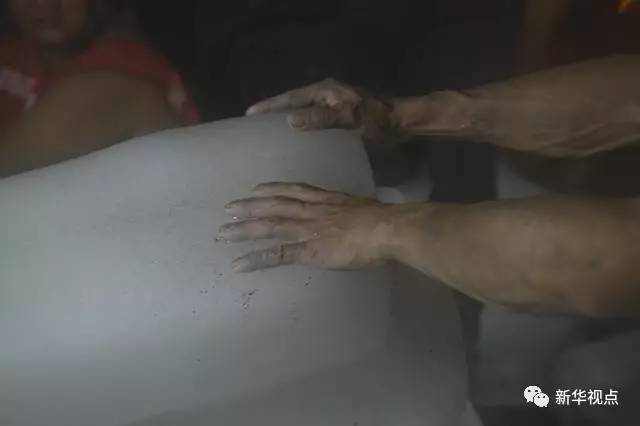  图为施工人员把手放到冰块上降温