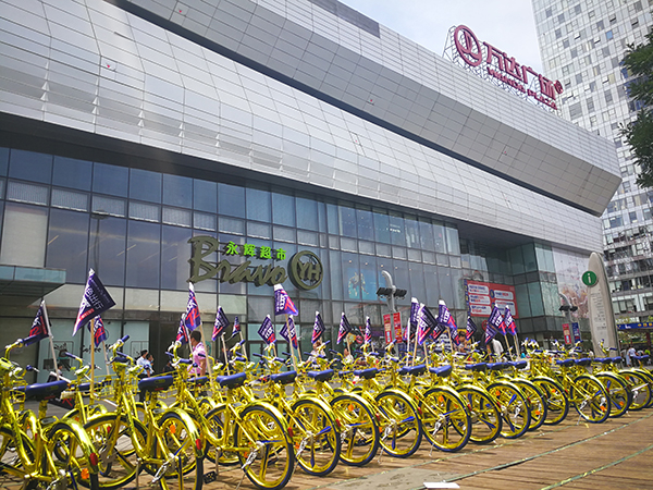 酷骑新推出的金色共享单车被摆放在通州万达广场前的空地上展示