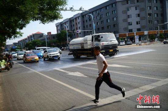 呼和浩特街头，运行洒水车给地面降温。 中新社记者 刘文华 摄