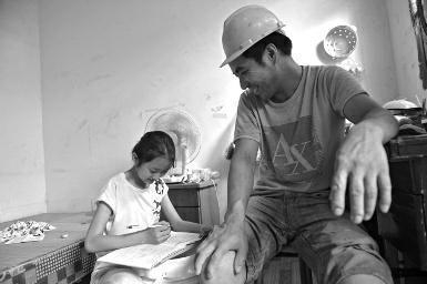  11岁张雅馨在小案板上写作业，一旁的张军才怜爱地看着女儿