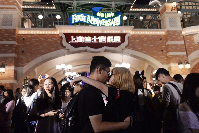 一对在迪士尼乐园门前拥吻的情侣