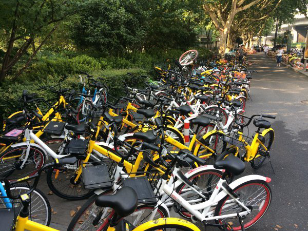 杭州一处人行道上挤满共享单车，行人只好走在非机动车道上。