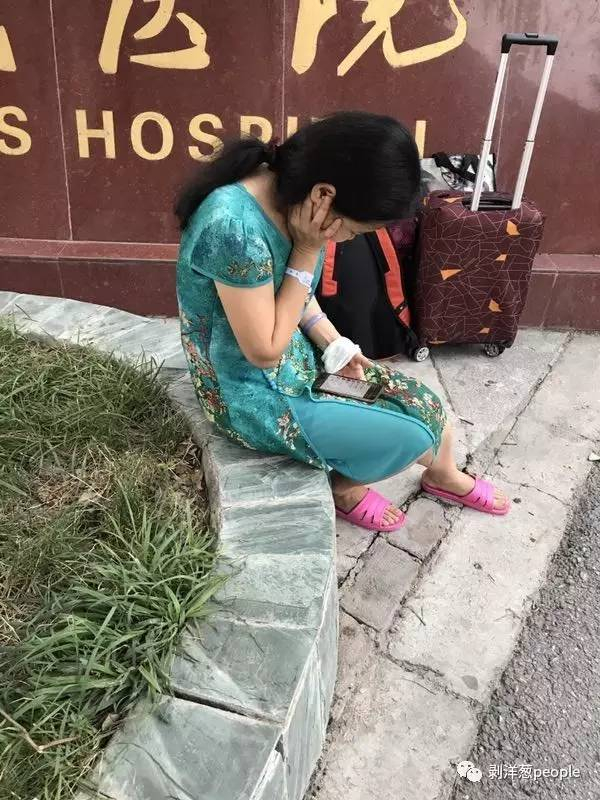 游客赵丽坐在九寨县人民医院门口等待回家的车。新京报记者刘珍妮 摄