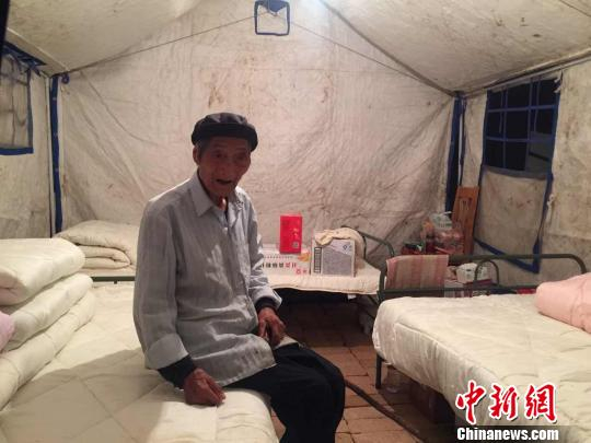 　　图为文县天池镇白马村受灾民众安置点帐篷内，90岁的老人王汝德独自坐着。床边放着挂面、矿泉水等救援物资。　南如卓玛 摄